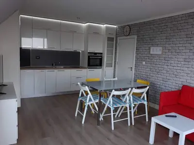 a kitchen with a table and chairs and a red couch at South Beach Apartments in Obzor