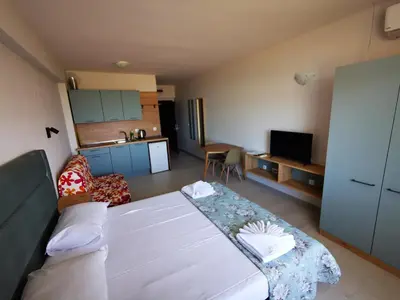 a living room with a large bed and a kitchen at Privately owned Studios Bora Bora in Nesebar