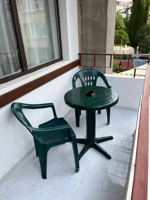 a green table and a chair on a porch at kaLe in Ravda