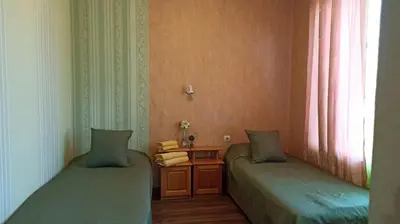 a room with two twin beds and a table at Панорама in Pomorie