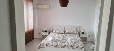 a white bedroom with a bed and two night stands at Polonia - KEMNI in Burgas City