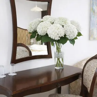 a vase of flowers on a table in front of a mirror at Luxury Studio in Sunny Beach with Pool, 5 Mins Walk to Beach in Sunny Beach