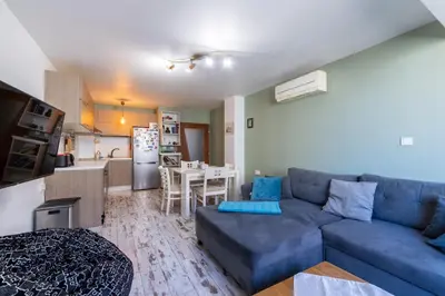 a living room with a blue couch and a kitchen at Bright City-Center Flat for 4 Guests in Varna City