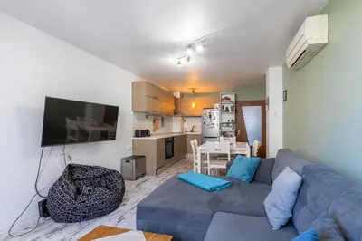 a living room with a blue couch and a kitchen at Bright City-Center Flat for 4 Guests in Varna City