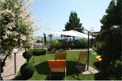 a group of chairs sitting in a yard with an umbrella at Family house ''Siema'' in Nesebar