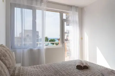 a pair of slippers sitting on a bed in front of a window at Soleil Bleu Beachfront Getaway in Nesebar