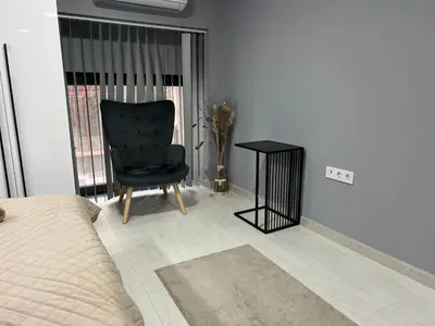 a bedroom with a black chair and a table at Varna Central Seaside Suite in Varna City
