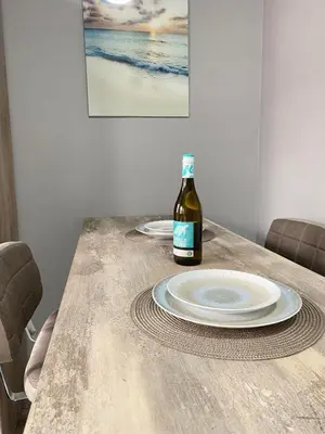 a bottle of wine sitting on a wooden table with plates at NJ Collection in Varna City