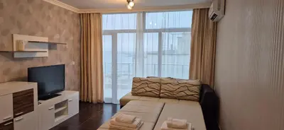 a living room with a couch and a television at East Beach Marina View Apartment in Sveti Vlas