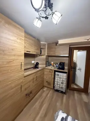 a kitchen with wooden cabinets and a chandelier at Студио-Джени in Burgas City