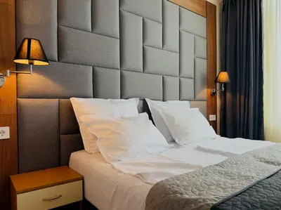 a bedroom with a large white bed with a large headboard at Слънчев Бряг Какао с басейн плаж in Sunny Beach