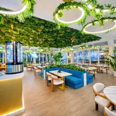 a restaurant with tables and chairs and plants at Harmony Suites Grand Resort-15 Private Apartment in Sunny Beach