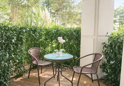 a table with two chairs and a vase with a flower at Harmony Suites Grand Resort-15 Private Apartment in Sunny Beach