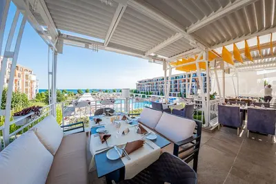 a restaurant with tables and chairs on a balcony at Premier Fort Beach Aparthotel - Sunny Beach in Sveti Vlas