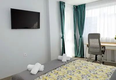 a bedroom with a bed and a chair and a television at Stylish 2BR Apartment with Underground Parking, Varna by Flat Manаger in Varna City