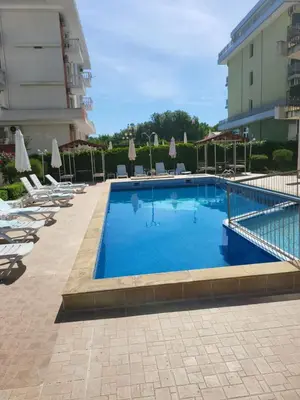 a swimming pool with chairs and umbrellas next to a building at Luxury apartment opposite Kakao in Sunny Beach