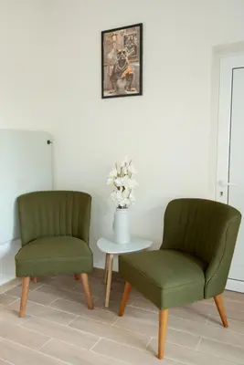 two green chairs and a table with a vase of flowers at Леглото in Topoli