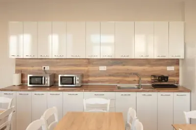 a kitchen with white cabinets and a table with chairs at Леглото in Topoli