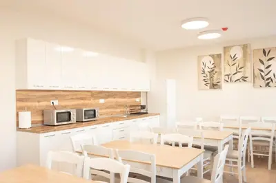 a kitchen with white cabinets and white tables and chairs at Леглото in Topoli