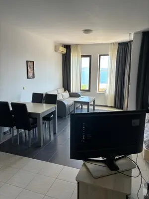 a living room with a tv and a couch and a table at Beachside apartment - 100 meters from the sea in Chernomorets