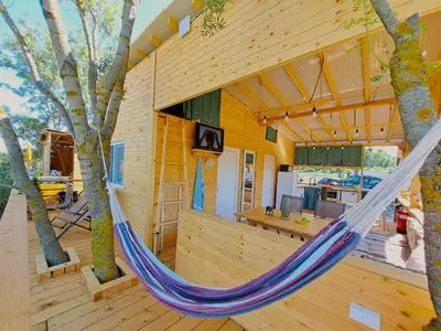 a hammock in the middle of a house with trees at Бунгало Лимонада in Chernomorets