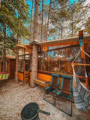 a cabin with two chairs and a hammock in the woods at Бунгало Борче in Burgas City
