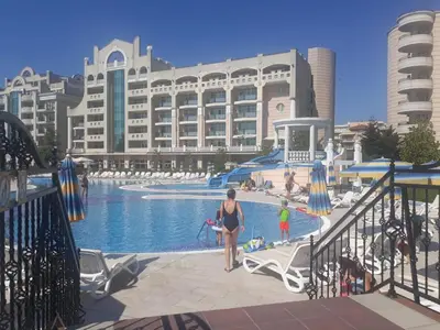a woman standing next to a swimming pool in front of a building at Specious apartment near beautiful beach Pomorie in Pomorie