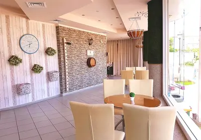 a restaurant with a table and chairs and a clock on the wall at Hotel Andre in Burgas City