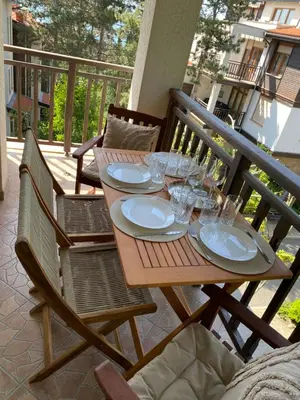 a wooden table with plates and glasses on a balcony at AJ Apartment 3, Santa Marina Holiday Village, Sozopol in Sozopol