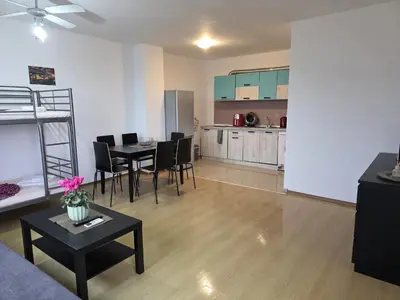a living room with a dining table and a kitchen at Perla View Apartment in Primorsko