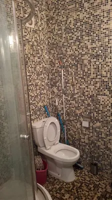 a bathroom with a toilet in a tiled wall at Апартамент in Burgas City