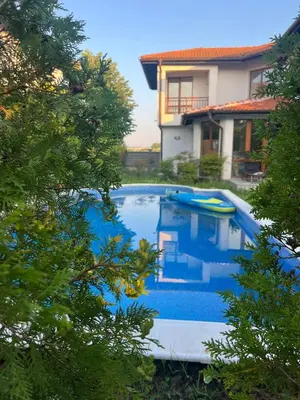 a blue swimming pool in front of a house at Villa LUNA in Kableshkovo
