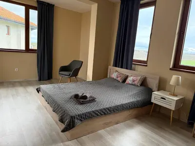 a bedroom with a bed and a chair and windows at Villa LUNA in Kableshkovo