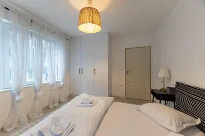a white bedroom with a bed and a window at Central 2BR - Workspace with Elevator in Varna City