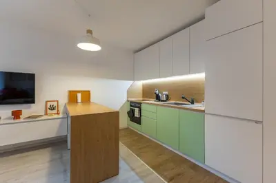 a kitchen with green and white cabinets and a tv at Central 2BR - Workspace with Elevator in Varna City