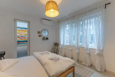 a white bedroom with a bed and a window at Central 2BR - Workspace with Elevator in Varna City