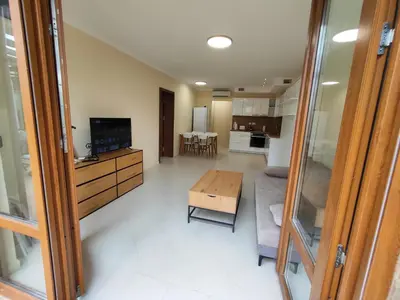 a living room with a table and a kitchen at Santa Marina Breeze in Sozopol