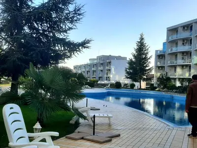 a swimming pool with two white chairs next to a building at Atlantis 8016 in Burgas City