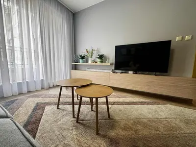 a living room with two tables and a flat screen tv at 1BD Apartment next to the Sea Garden by Flat Mаnager in Burgas City