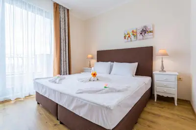 a bedroom with a large bed with a large window at Gardenia Beach Palace Aparthotel in Pomorie
