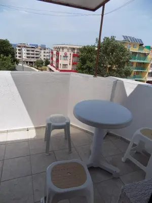 a table and stool on a balcony with an umbrella at Rali Apartments in Kiten