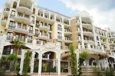 a large white building with palm trees in front of it at Harmony Suites - Dream Island in Sunny Beach