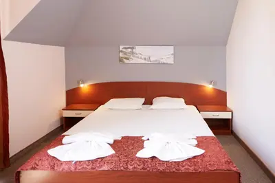 a bedroom with a bed with white sheets and pillows at Guesthouse Kirov in Ravda
