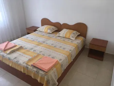 a bed with two pillows and two tables on it at Къща за гости Кадиеви in Primorsko