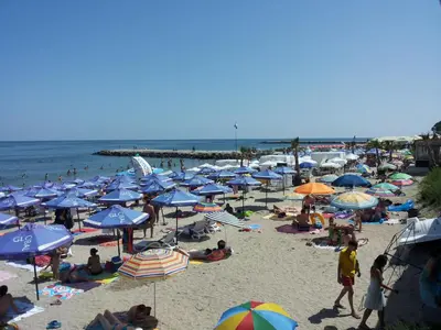 a crowd of people on a beach with umbrellas at Апартаменти и стаи Анхиало in Pomorie
