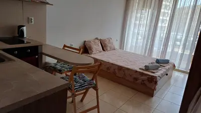 a small room with a bed and a table and a kitchen at Апартаменти и стаи Анхиало in Pomorie