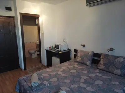 a small bedroom with a bed and a microwave at Апартаменти и стаи Анхиало in Pomorie