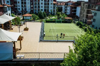 two people playing tennis on a tennis court in a city at Family hotel Apolon in Nesebar