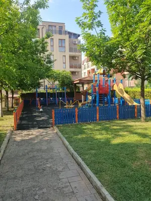a playground in a park with a blue fence at Family hotel Apolon in Nesebar