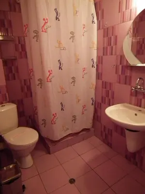 a bathroom with a shower curtain with a toilet and sink at Guest House Olimpiya in Sveti Vlas